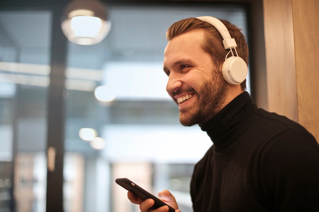 Como o Bitcoin disparou +47% em fevereiro e o impacto nas altcoins 1 Homem branco sorrindo, ele tem cabelos loiros escuros e headphone branco. Imagem ilustrativa.